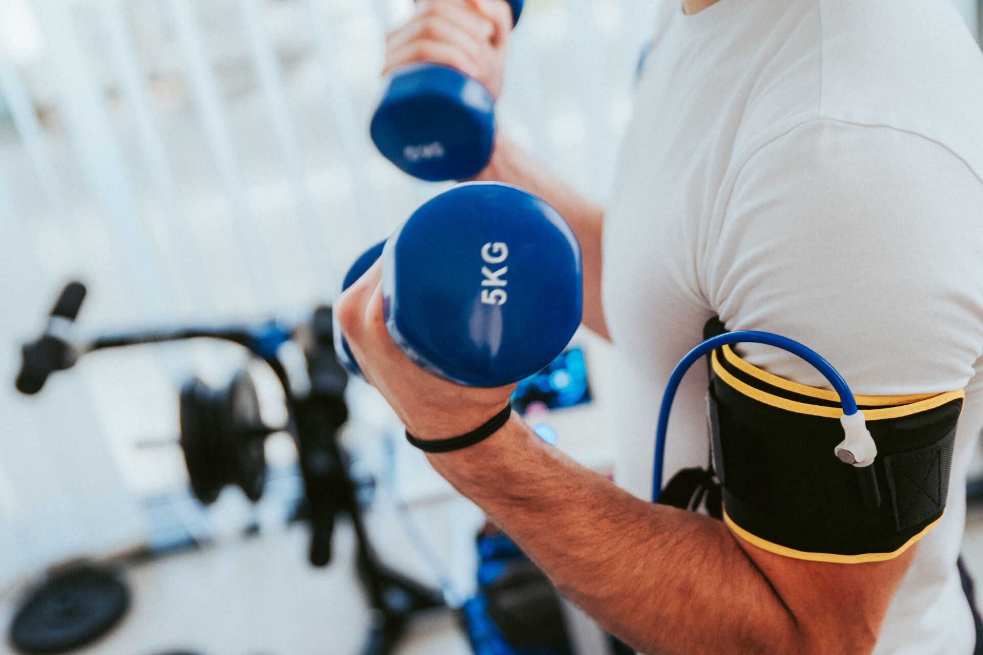 Man lifting weights with blood flow restriction cuffs on